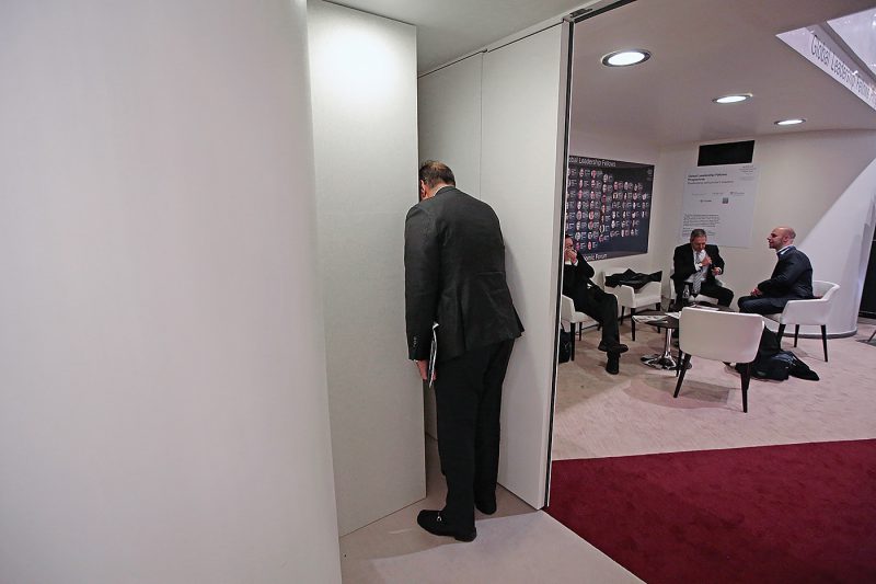 An attendee makes a private phone call behind a wall screen between sessions during the World Economic Forum (WEF) in Davos, Switzerland, on Friday, Jan. 22, 2016. World leaders, influential executives, bankers and policy makers attend the 46th annual meeting of the World Economic Forum in Davos from Jan. 20 - 23. Photographer: Jason Alden/Bloomberg